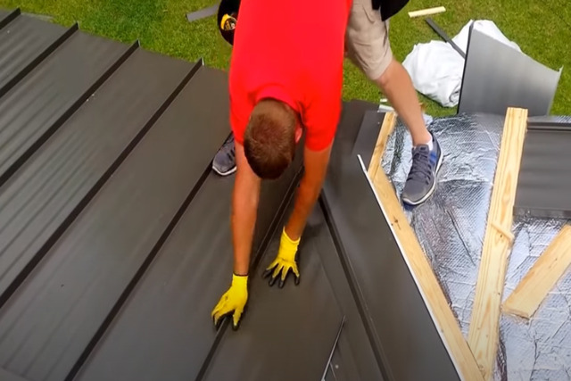 Roofing worker installing standing seam roof