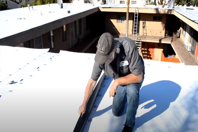 Worker checking commercial flat roofing