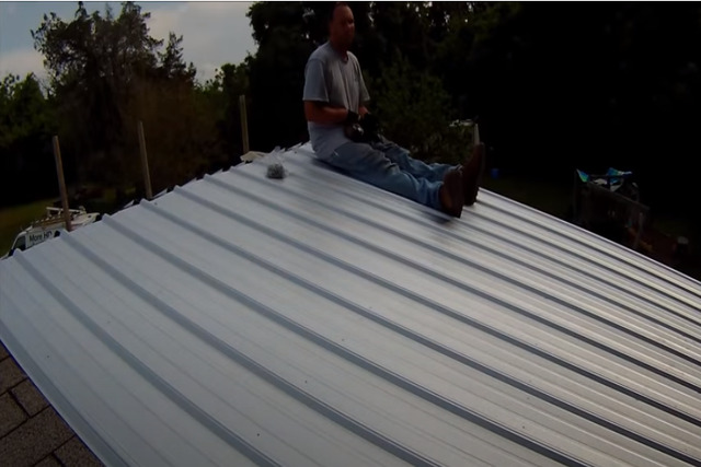 Worker installing metal roof on the house