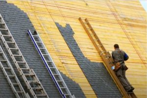 Workers placing shingles on the roof